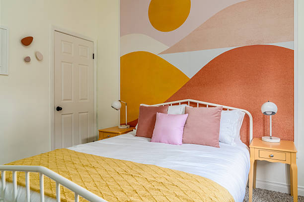 Chambre papier peint coline rose et orange, lit avec draps blancs, coussins rose et plaid jaune